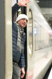 Man waving hand while standing in train