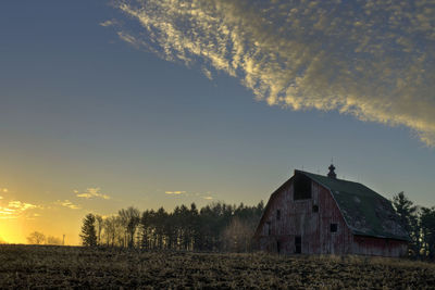 House on field against sky during sunset