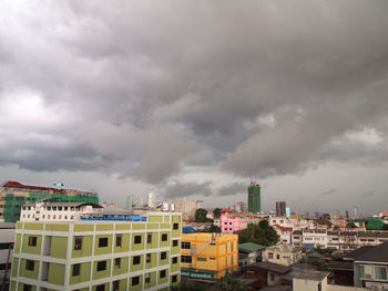 Buildings in city against dramatic sky