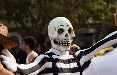 Close-up of man with arms outstretched wearing a skeleton mask a dead head mask a crane mask