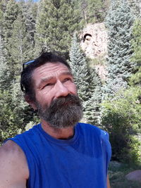 Portrait of man with arms raised against trees