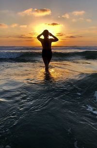 Silhouette man standing on beach against sky during sunset