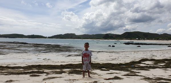 Rear view of man standing at beach against sky