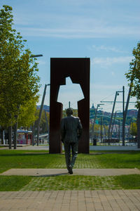 Rear view of man sculpture in city against sky