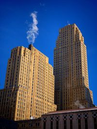 Low angle view of skyscrapers against clear blue sky