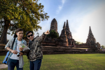 Young couple standing at temple against sky