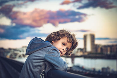 Boy looking away against sky