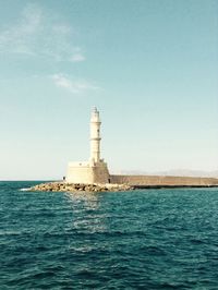 Lighthouse by sea against sky