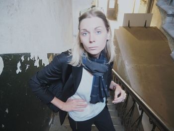 Portrait of young woman standing against wall