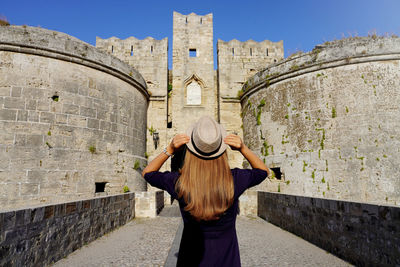 Tourist girl visiting the old fortifications of rhodes city, greece. unesco world heritage site.