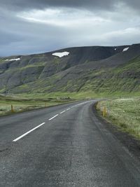 Road leading towards mountain against sky