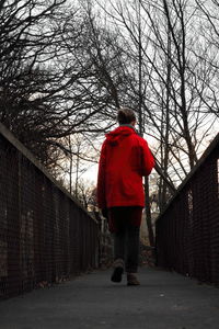 Rear view of man walking on red road