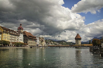 View of buildings at waterfront against cloudy sky