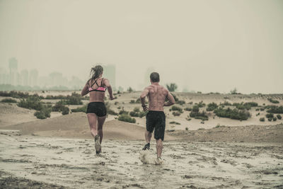 Rear view of people running on beach