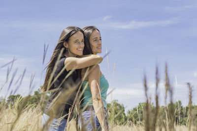 Happy young woman on field against sky