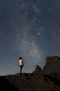 Rear view of man standing on mountain against sky at night