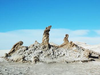 Rock formation on sea shore against sky