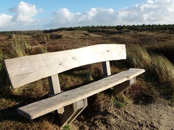 Bench on field against sky