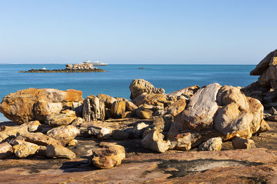 Rocks on sea shore against clear sky