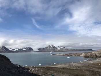 Scenic view of sea by snowcapped mountains against sky