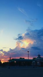 Silhouette factory against sky at sunset