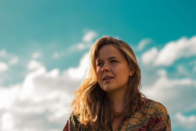 Smiling young woman looking away with sky in background