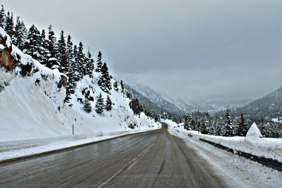 Snow covered road by snowcapped mountain against sky