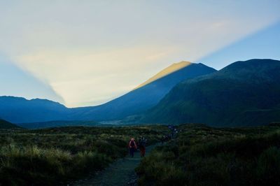 Rear view of people walking on mountain against sky on a sunrise 