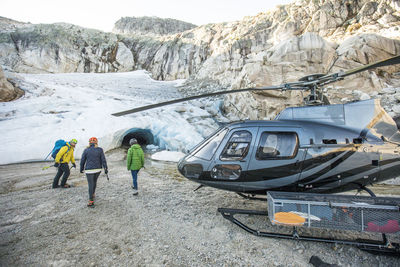 A mountain guide approaches a glacial ice cave with tour clients.