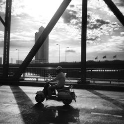 People sitting on bench against cloudy sky