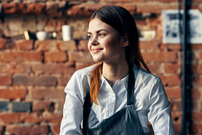 Portrait of a smiling young woman standing against wall