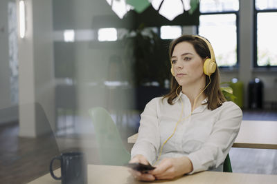 Young woman using mobile phone while sitting on table