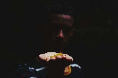 Close-up of hand holding apple against black background