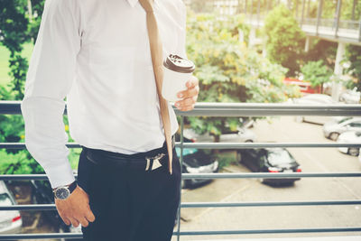 Midsection of man holding ice cream standing outdoors