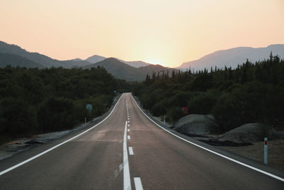 Road leading towards mountains against sky