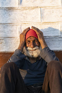 Portrait of young man wearing hat standing against wall