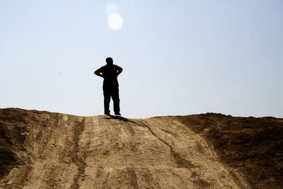 Rear view of man standing on mountain against clear sky