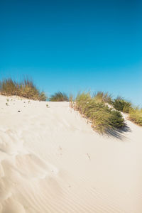 Scenic view of desert against clear blue sky