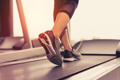 Low section of woman walking on treadmill