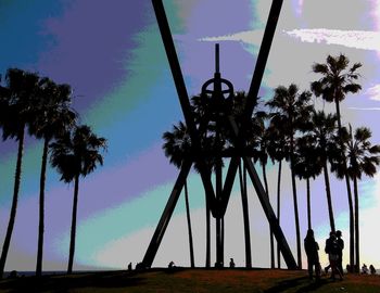 Silhouette people standing by palm trees against sky