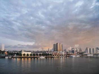 Buildings by river against sky in city