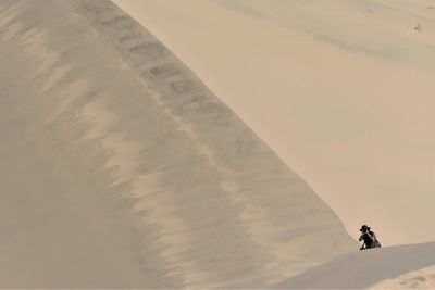 Man on sand dune in desert against sky