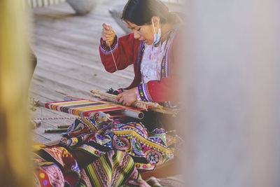 Indigenous woman showing traditional weaving technique and textile making in the andes mountain