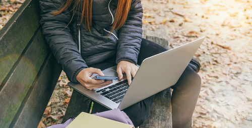 Girl study sitting on a bench in the park. teen using laptop and smartphone. student doing homework