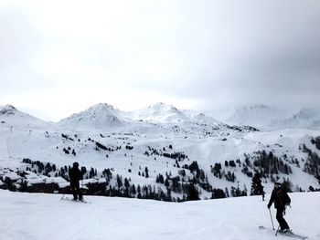 Rear view of people on snowcapped mountains against sky