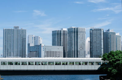 Modern buildings by river against sky in city