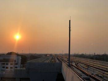 Railroad tracks amidst buildings against sky during sunset