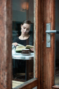 Beautiful woman sitting by table with book