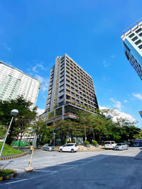 City street by modern buildings against sky