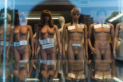 Full length of shirtless young woman standing in glass